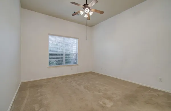 an empty room with a window and a ceiling fan