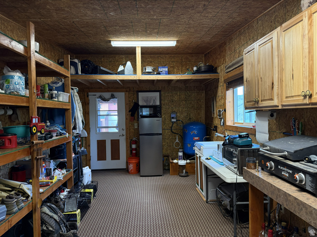 2006 Swenson Valley Road Bancroft, ID 83217 - Photo 45 of 51 Utility room featuring wood paneling, wall-mounted cabinetry, built-in shelving, a window, and patterned flooring