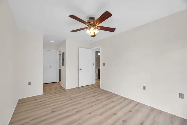 a view of empty room with wooden floor and ceiling fan