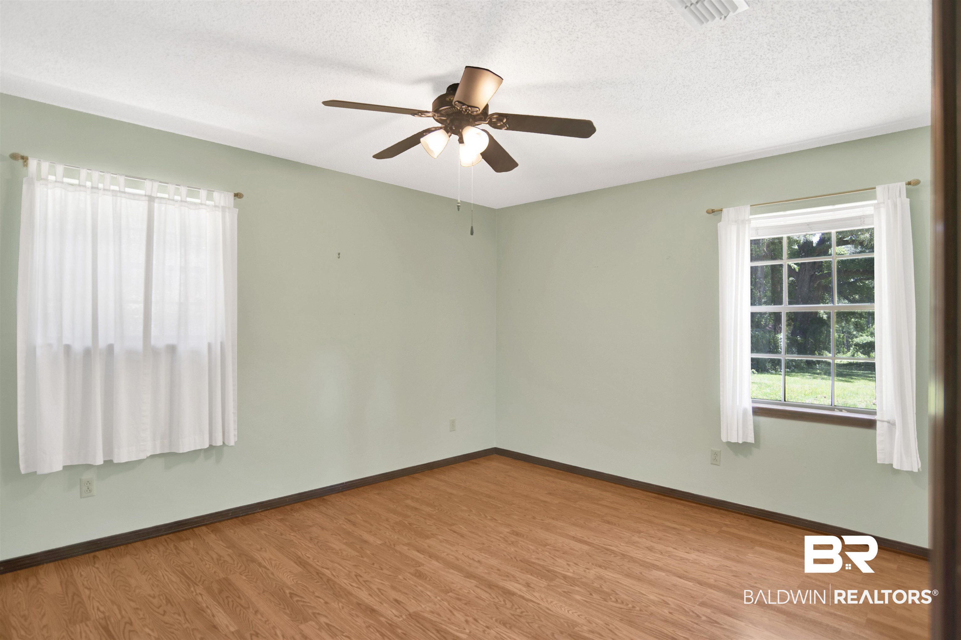 30888 Cemetery Road Daphne, AL 36527 - Photo 19 of 36 Room featuring wood-finish flooring, light green walls, a ceiling fan with integrated lighting, and two windows