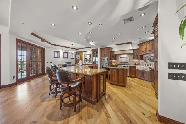 a large kitchen with stainless steel appliances granite countertop a large stove a sink dishwasher and a microwave oven with wooden floor