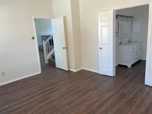 a view of empty room with wooden floor and bathroom