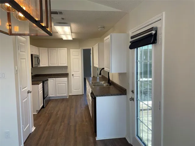 a kitchen with stainless steel appliances granite countertop a refrigerator a sink dishwasher a stove and white countertops with wooden floor