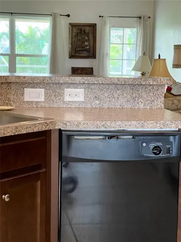 a kitchen with kitchen island granite countertop a stove a sink dishwasher and white cabinets with wooden floor