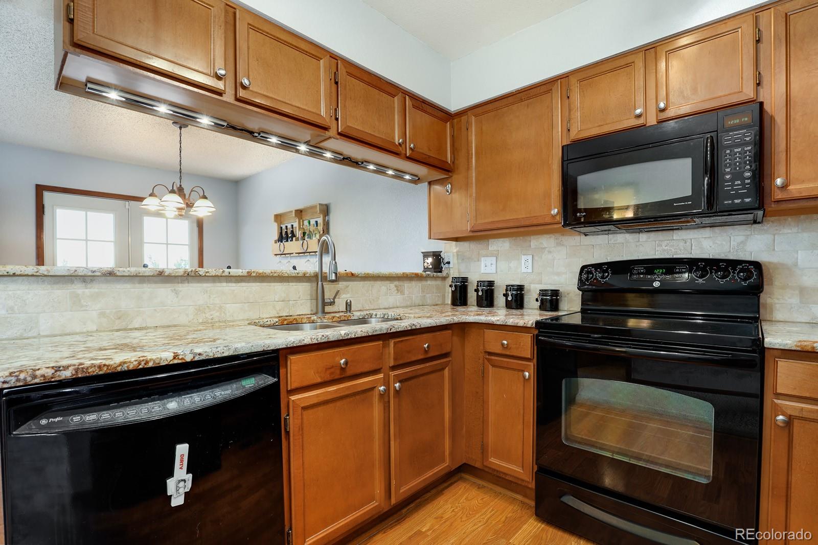1055 Cobblestone Drive Highlands Ranch, CO 80126 - Photo 7 of 31 a kitchen with stainless steel appliances granite countertop a stove microwave and sink