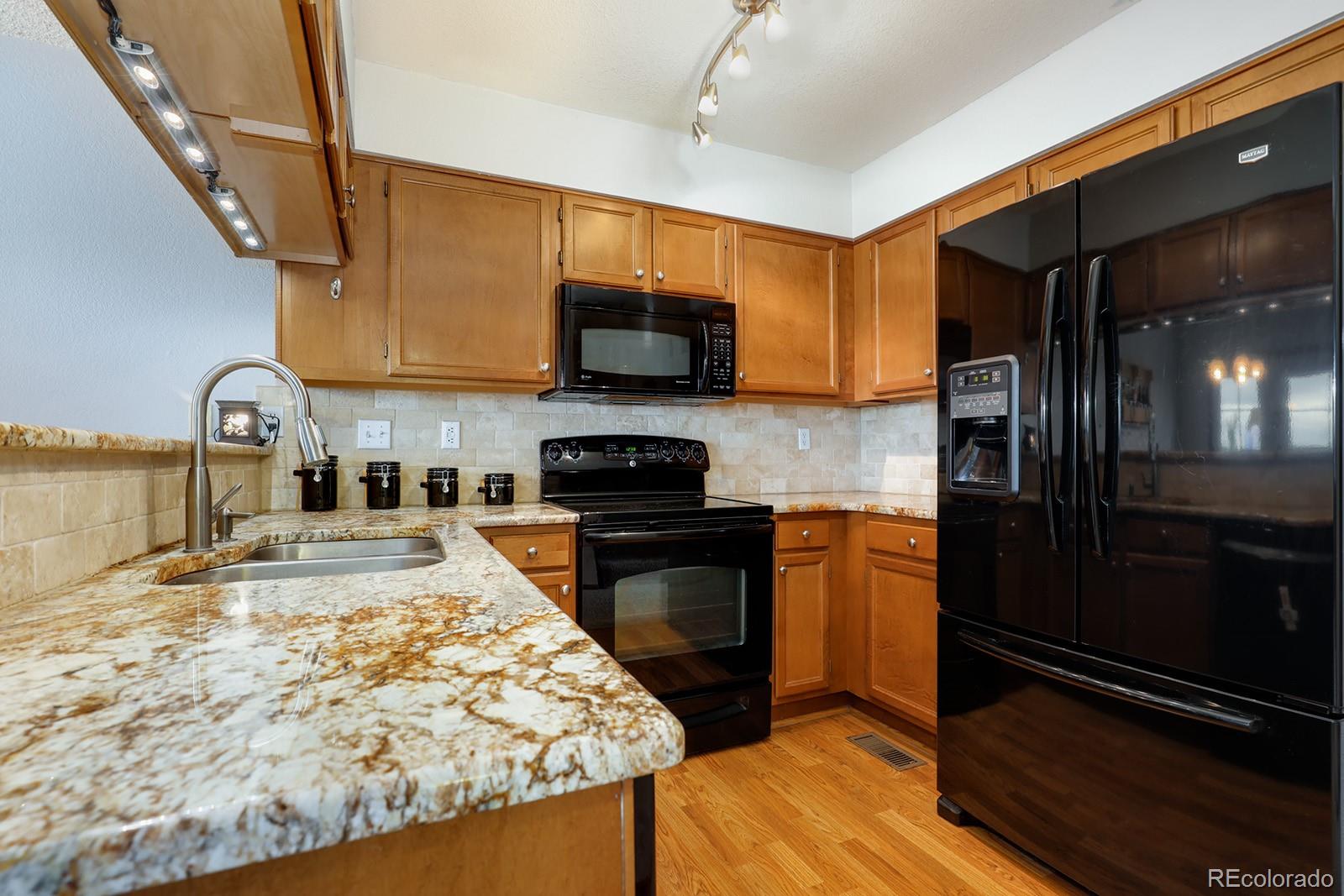 1055 Cobblestone Drive Highlands Ranch, CO 80126 - Photo 8 of 31 a kitchen with stainless steel appliances granite countertop a stove refrigerator and a microwave
