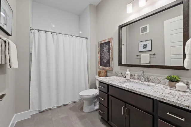 a bathroom with a granite countertop sink and a mirror with toilet