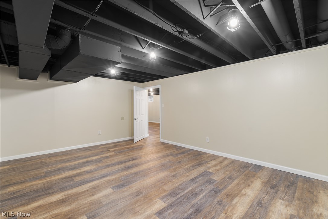 1075 Northeast River Road Lake Milton, OH 44429 - Photo 26 of 34 Finished room featuring wood-finish flooring, light-toned walls, and an exposed black painted ceiling with industrial-style lighting fixtures