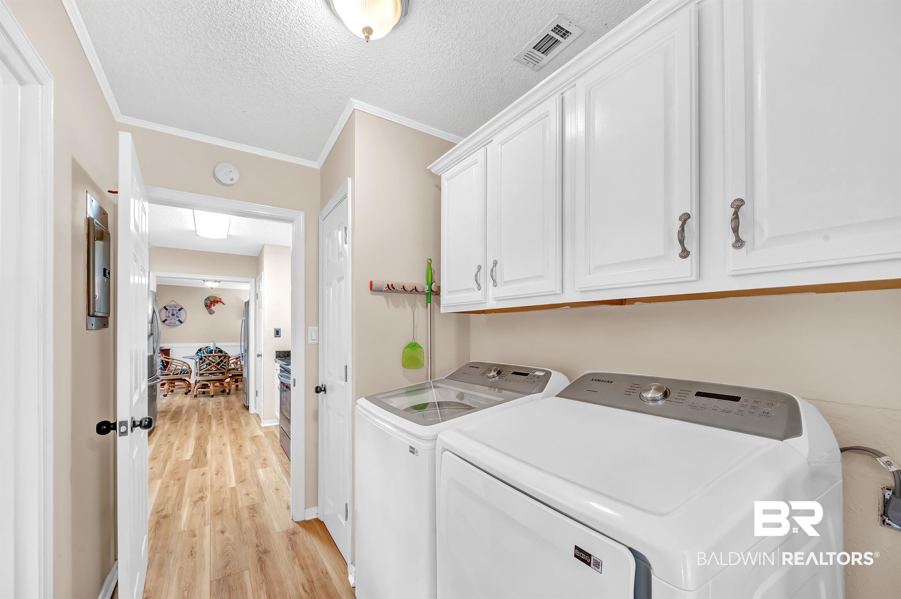 24551 Wolf Bay Drive Foley, AL 36535 - Photo 31 of 59 Laundry area with cabinet space, washing machine and clothes dryer, ornamental molding, light wood-style flooring, and a textured ceiling