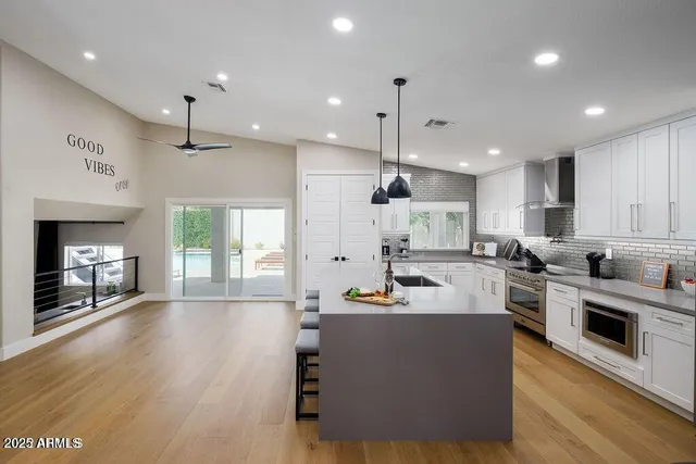 a large white kitchen with lots of counter space a sink refrigerator and cabinets