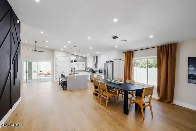 a dining hall with stainless steel appliances kitchen island granite countertop a dining table chairs and view living room