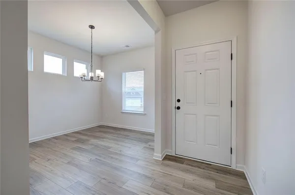 an empty room with wooden floor mirror and windows