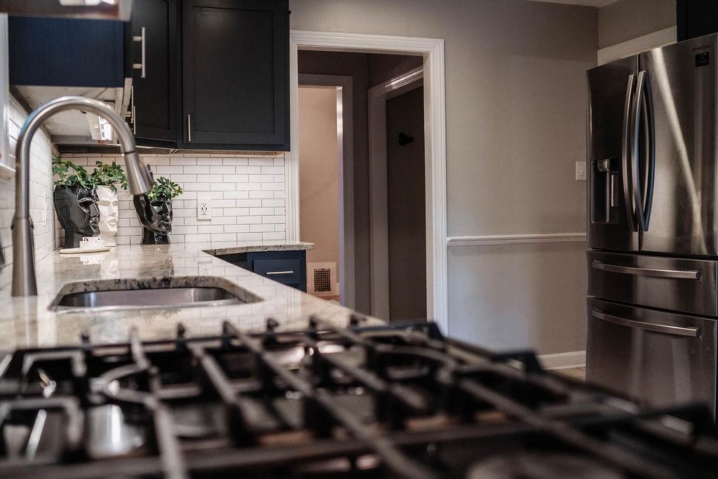 1925 Nelson Avenue Memphis, TN 38104 - Photo 12 of 39 Kitchen featuring stainless steel fridge, subway tile backsplash, granite countertops, and gas stovetop