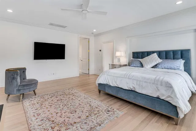 a spacious bedroom with a bed and a flat screen tv