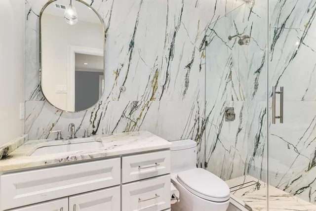 a bathroom with a granite countertop sink mirror vanity and toilet