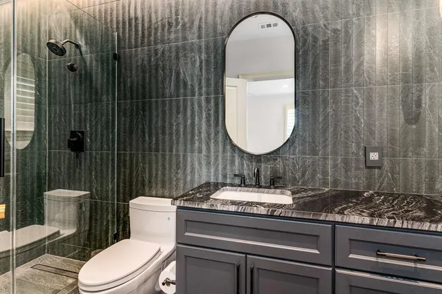 a bathroom with a toilet sink vanity granite and mirror