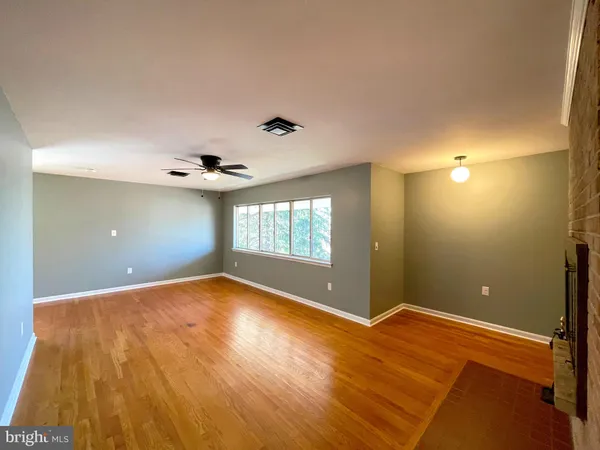 a view of an empty room with window and wooden floor