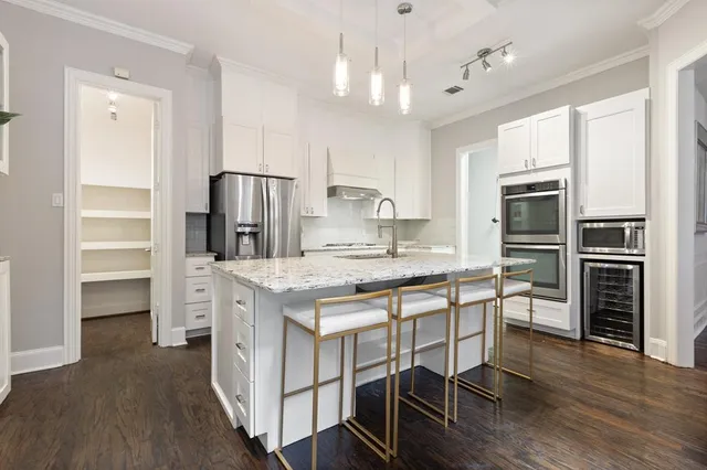 a kitchen with stainless steel appliances granite countertop a table chairs stove and refrigerator