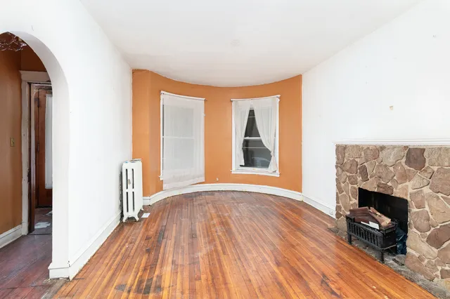 a view of empty room with wooden floor and fireplace