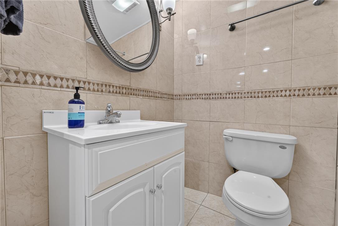 220 Pennbrook Road Stroudsburg, PA 18360 - Photo 45 of 60 A compact bathroom featuring tiled walls, a vanity with sink, and a toilet, perfect for daily routines.