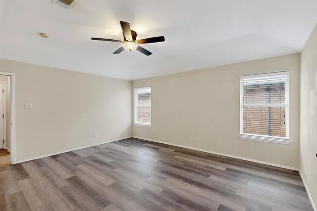 a view of empty room with wooden floor and fan
