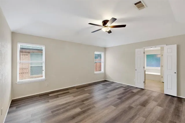 a view of empty room with wooden floor and ceiling fan
