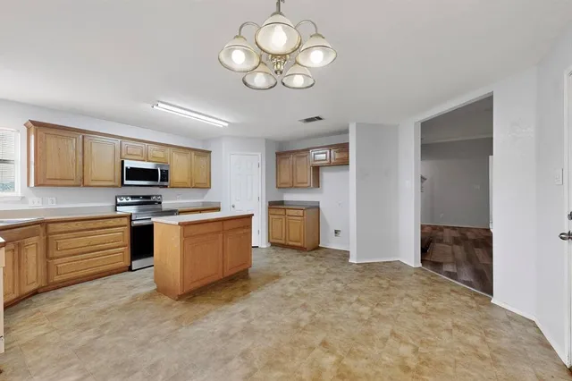 a kitchen with granite countertop a stove top oven a sink dishwasher a dining table and chairs with wooden floor