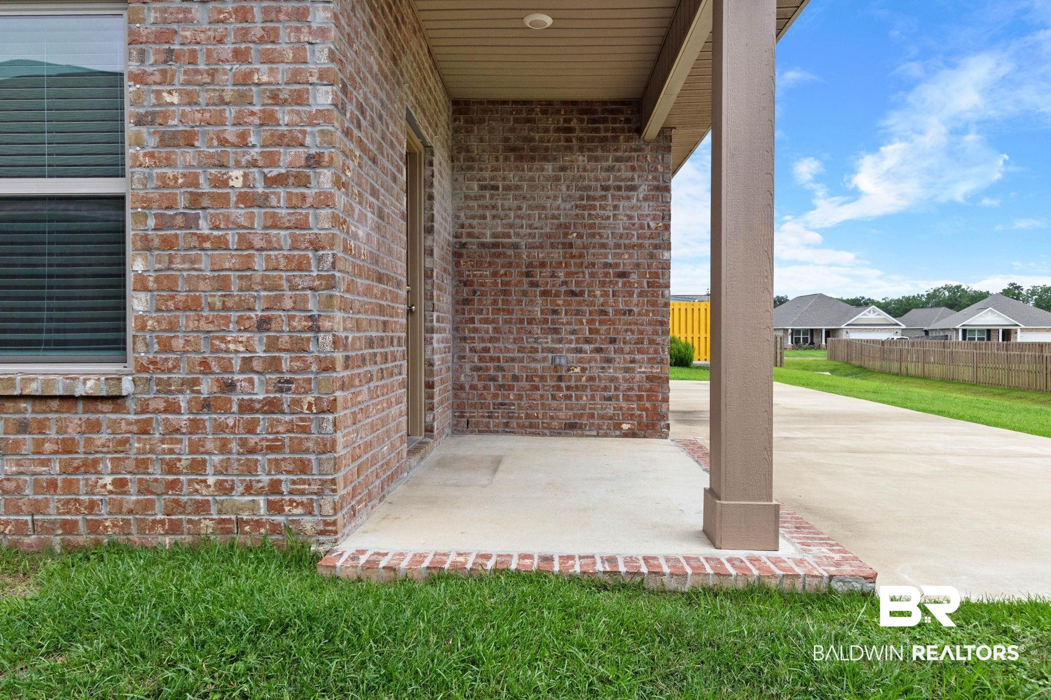 1710 Grouse Street Foley, AL 36535 - Photo 70 of 76 Brick exterior featuring a concrete patio, a covered entryway, and a window with blinds