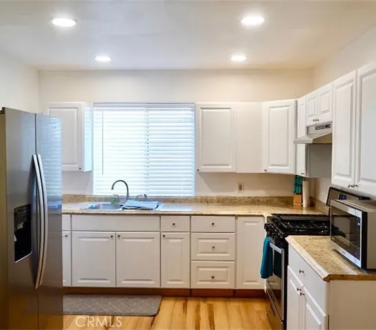 a kitchen with stainless steel appliances granite countertop a sink stove and refrigerator