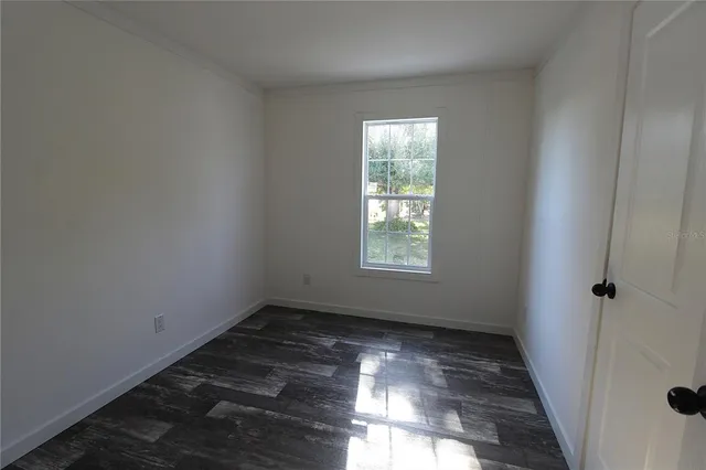 a view of empty room with wooden floor and windows
