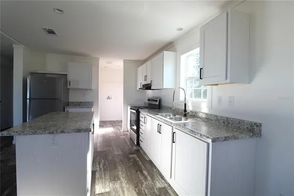a kitchen with granite countertop a refrigerator and a sink