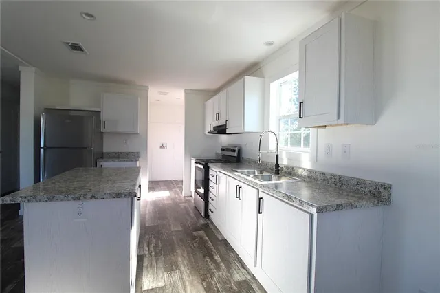 a kitchen with granite countertop a refrigerator and a sink