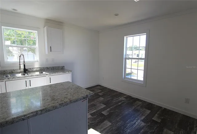 an empty room with wooden floor a ceiling fan and windows