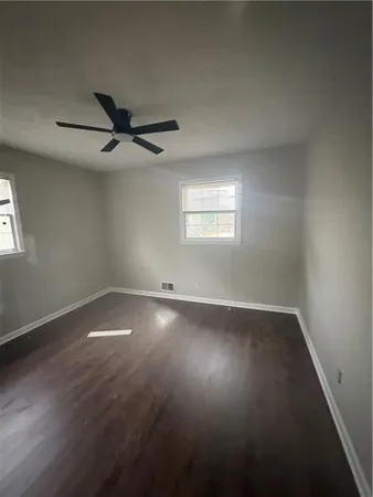 a view of an empty room with wooden floor and a window