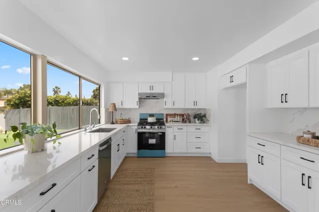 a large white kitchen with stainless steel appliances granite countertop a stove a sink and white cabinets