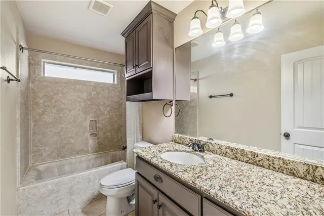 a bathroom with a granite countertop sink a toilet and bathtub