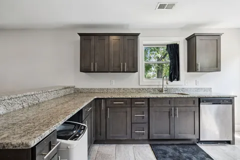 a kitchen with stainless steel appliances granite countertop a refrigerator a sink a stove and oven