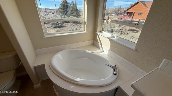 a spacious bathroom with a granite countertop double vanity sink a mirror and a bathtub