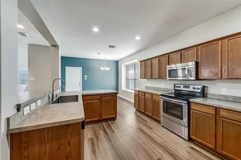 a kitchen with stainless steel appliances granite countertop wooden cabinets a stove top oven a sink and dishwasher
