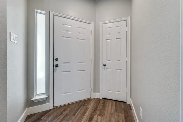 a view of an empty room with closet and wooden floor