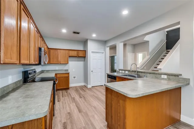 a kitchen with stainless steel appliances granite countertop sink stove refrigerator and wooden floor