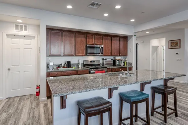 a kitchen with granite countertop a stove a sink and a refrigerator