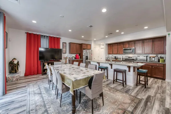 a kitchen with stainless steel appliances kitchen island granite countertop a sink a stove a dining table and chairs