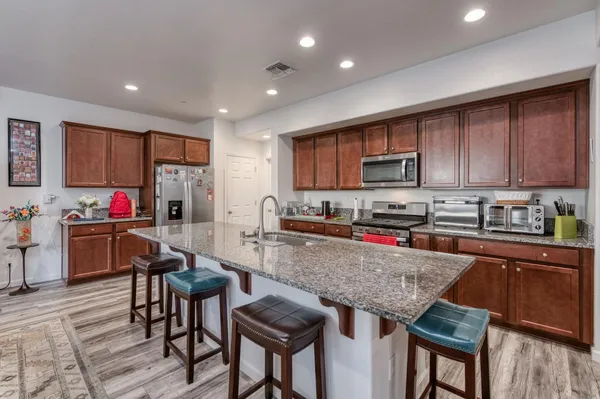 a kitchen with granite countertop a stove top oven a sink dishwasher a dining table and chairs with wooden floor