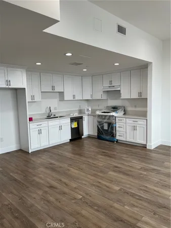 a large kitchen with cabinets wooden floor and stainless steel appliances