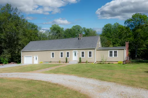 a house that has a big yard with plants and large trees