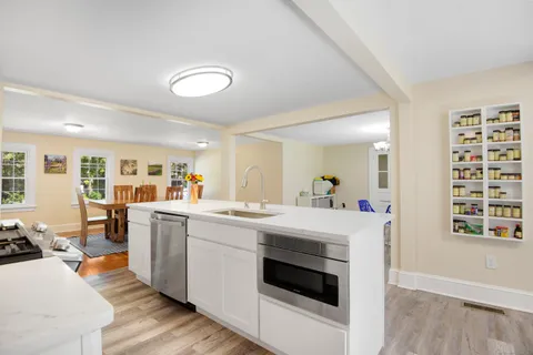 a kitchen with a stove a refrigerator and a dining table with wooden floor