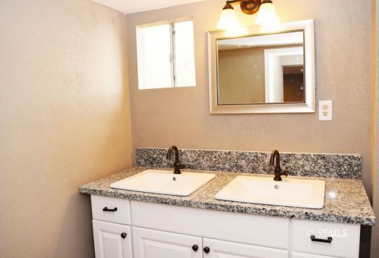 1130 South Guam Street Ridgecrest, CA 93555 - Photo 7 of 12 a bathroom with a granite countertop sink and a mirror