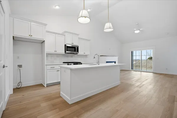 a view of kitchen and empty room with wooden floor