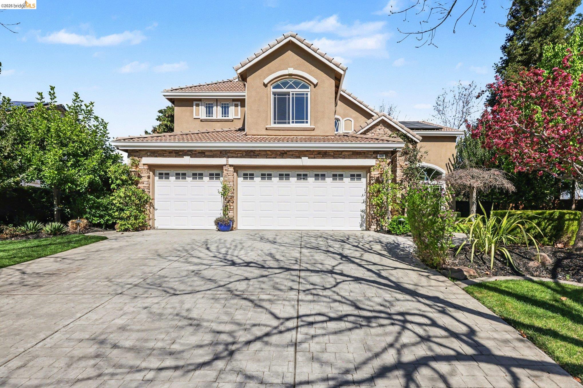 View of front of home featuring stucco siding, concrete driveway, solar panels, and a tiled roof